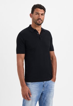 Zwarte korte mouw polo gemaakt van gladde stof, met een klassieke kraag en drie knopen bij de halslijn, gecombineerd met lichtblauwe jeans.