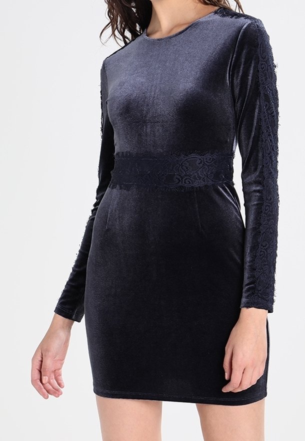 Sjöblå sammetsklänning med figursydd silhuett, långa ärmar med spetskant och en bred spetssnar för detaljer i midjan. Mjuk textur och slät finish.