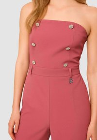 Tuta senza spalline rosa con decorazioni floreali argentate e cintura, con un dettaglio con logo "R" sulla vita, tessuto dalla texture liscia.