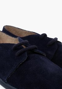 Scarpe in suede blu navy con forma arrotondata, due occhielli con lacci e una texture morbida. Fodera interna di colore più chiaro.