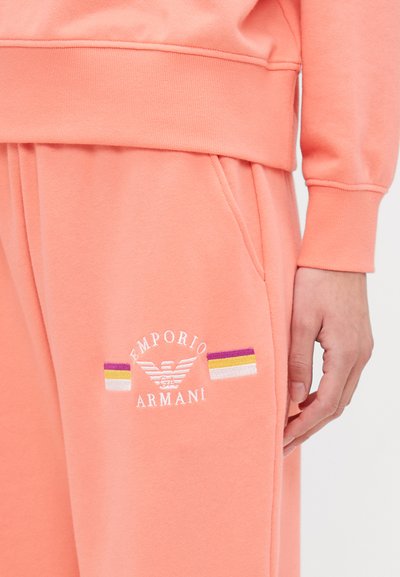 Koralo spalvos džemperis su išsiuvinėtu "Emporio Armani" logotipu ir dryžuotais akcentais purpurine, geltona ir balta spalvomis. Minkšta, tekstūruota medžiaga, laisvas siluetas.