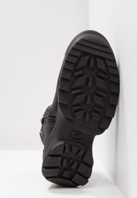 Semelle noire de bottes avec un motif de bande de roulement profond et une indication de taille 37, présentée verticalement sur fond blanc.