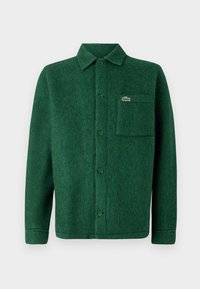 Chemise verte à boutons en laine texturée, avec un col, des manches longues et une poche poitrine avec un logo.