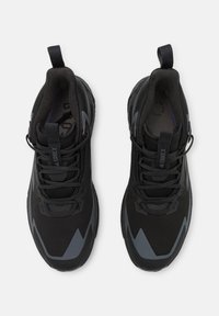 Scarpe da ginnastica nere con una parte superiore testurizzata, accenti grigi, un occhiello di presa e chiusura con lacci. Presentano una suola cushioned per il comfort.