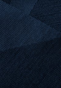Tessuto texturizzato di un profondo blu navy con un aspetto intrecciato, che mostra linee diagonali e una superficie morbida e tattile.
