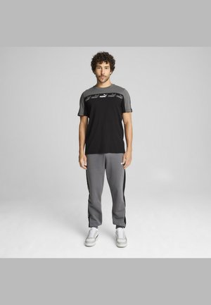 Black and gray athletic outfit with a logo on the shirt, featuring a round neck and short sleeves. Gray pants with side accents.