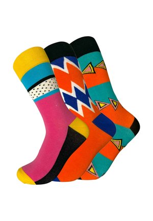 Trois chaussettes colorées avec des motifs géométriques : rose et jaune avec des points noirs, orange et bleu avec des zigzags, et bleu sarcelle avec des triangles orange.