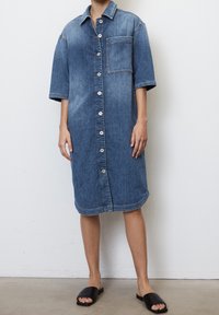 Sukienka koszulowa z dżinsu, jasnoniebieska, z guzikami z przodu, krótki rękaw, pojedyncza kieszeń na klatce piersiowej, do kolan, połączona z czarnymi klapkami.