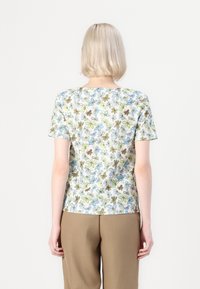 Top a maniche corte con motivo floreale, con accenti blu, verdi e marroni su uno sfondo chiaro; tessuto morbido e scollatura a girocollo.