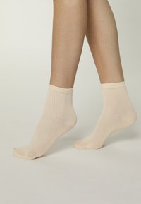 Calcetines beige de mezcla de algodón con textura acanalada y altura media hasta la pantorrilla. Presentan un puño suave y elástico para mayor comodidad y ajuste.