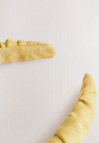 Yellow fabric gloves with a textured, ribbed pattern on the fingertips, featuring a soft, curved design and smooth seams.