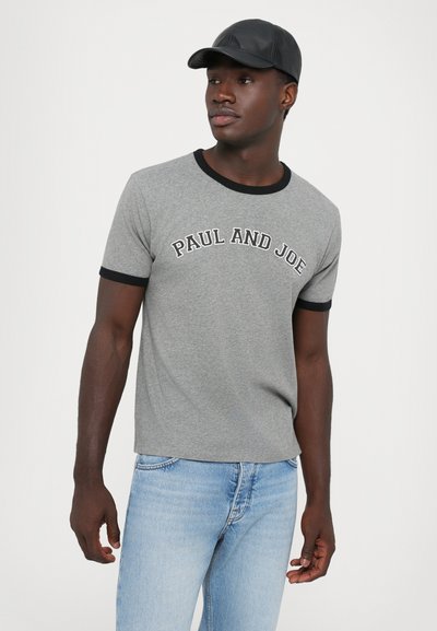 Gray short-sleeve t-shirt with black ribbed collar and cuffs featuring "PAUL AND JOE" in white text across the chest, paired with light blue jeans.