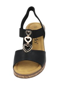 Zwarte sandaal met brede band, elastische hak en drie hartvormige metalen accenten. Kurk-textuur zool met een gevoerde tan voetbed.