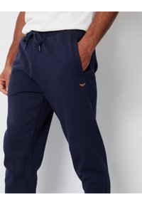 Marineblå sweatpants lavet af blød bomuldsblanding, med elastisk talje med snor og sidelommer. Lille emblem på forsiden.