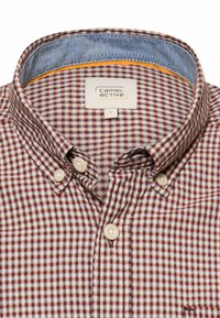 Koszula z kołnierzykiem na guziki w czerwono-biało-niebieską kratę z beżowymi guzikami, z metką "camel active" wewnątrz kołnierza.