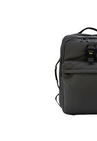 Mochila de tela negra con forma rectangular, que cuenta con un bolsillo frontal con cremallera, correas ajustables y un asa superior.