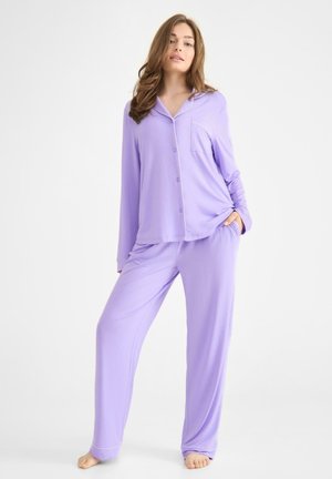 Lila pyjama set van zachte stof, met een knoopsluiting aan de bovenkant en een zak, en lange broek met een relaxte pasvorm en contrasterende zoomstiksel.