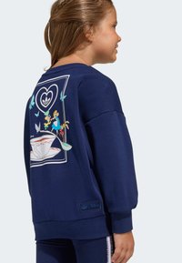 Námornícka modrá mikina s kresleným obrázkom na chrbte, obsahujúca postavy a motýle. Vyrobená z mäkkej, textúrovanej tkaniny.