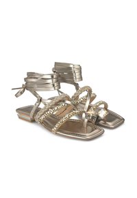 Metalen gouden platte sandalen met meerdere banden, versierd met rhinestones en een decoratieve faux edelsteen. Gevoerde voetbed en rubberen zool.