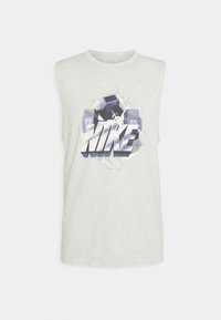 T-shirt sans manches en coton gris clair avec un logo Nike graphique audacieux en noir et blanc agrémenté d'accents verts. Texture lisse, col rond.