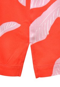 Helles rotes Material mit weißen Blattmustern. Verfügt über einen gespaltenen Saum an der Unterseite mit sauberem Stich und einer glatten, weichen Textur.