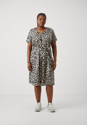 Leopard print short-sleeve dress with a V-neck, cinched waist, and knee-length skirt. Worn with white sneakers, featuring textured fabric.