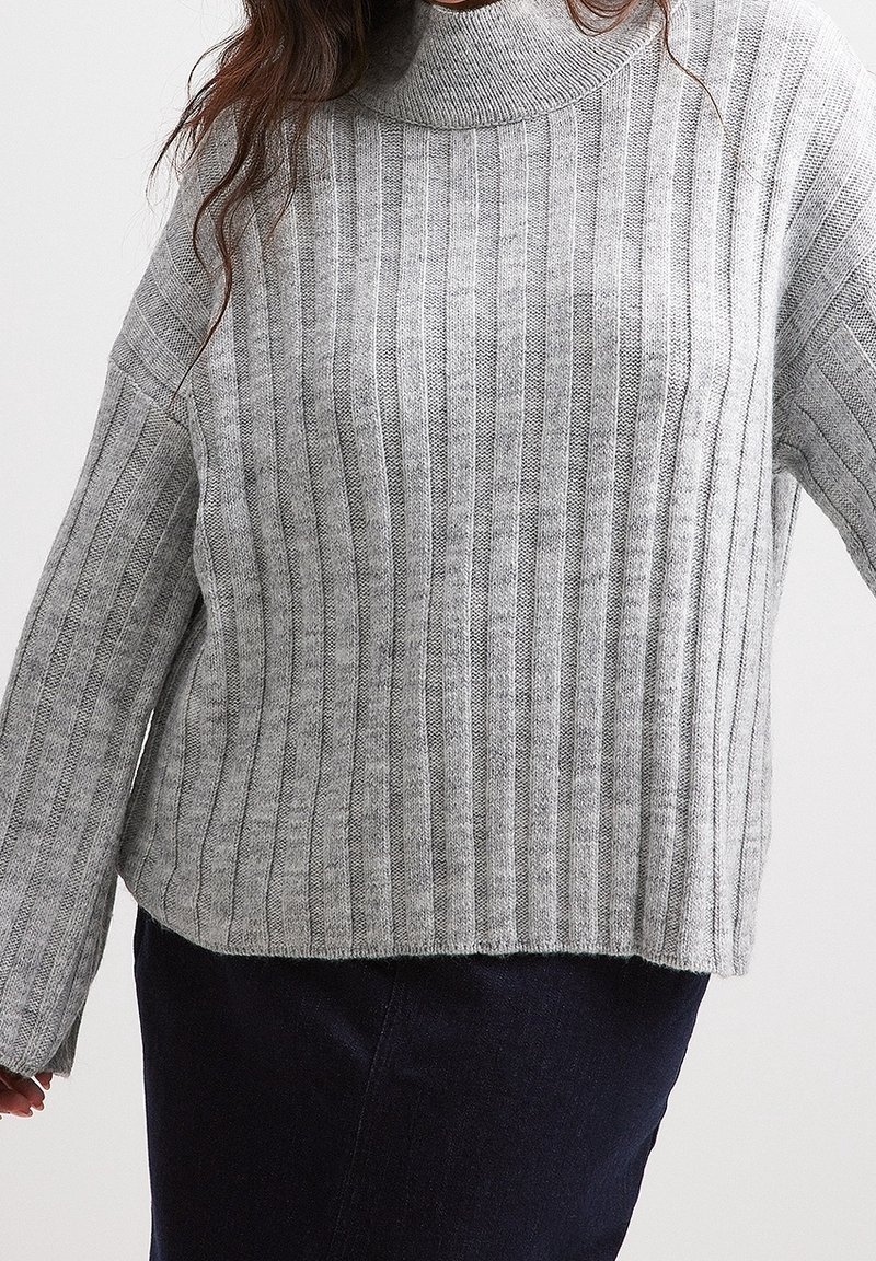 Grau gerippter Strickpullover mit hohem Kragen, weiten Ärmeln und lockerer Passform, der vertikale Streifen und eine weiche Textur aufweist.