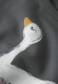 Tessuto grigio con una grande oca illustrata di colore bianco, con becco arancione e dettagli in nero, su una superficie morbida e texture.