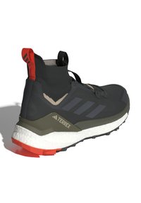 Chaussure de sport noire au design ressemblant à une chaussette, accents gris, tige texturée et semelle intermédiaire blanche avec un détail de semelle extérieure orange.