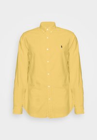 Långärmad gul skjorta med knappslå, krage och liten broderad mörk logotyp på vänster bröst.