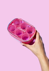 Estuche para rulos de cabello rosa con seis compartimentos transparentes, con un cierre holográfico y el logo "Mermade Hair", sostenido en una mano.