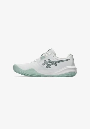 Weiße Sportschuhe mit einem schlanken Design, ausgestattet mit einer grün gefärbten Sohle, einem auffälligen schwarzen Logo und einer strukturierten Oberseite für Atmungsaktivität.