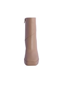 Botín de tobillo de imitación de cuero beige con un acabado suave, silueta esbelta y cremallera lateral. Presenta una suela con plataforma y acentos de diseño sin costuras.