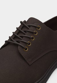 Καφέ καστόρινο παπούτσι με κορδόνια, στρογγυλά χάλκινα μεταλλικά οφθαλμοτρήματα και ταίριασμα καφέ κορδόνια, με μαύρη λαστιχένια σόλα.