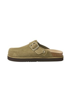 Chaussure à enfiler en suède vert olive avec une bride réglable à boucle, semelle intérieure en liège et semelle extérieure en caoutchouc foncé, vue de côté.