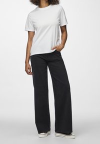 Vit bomullströja med korta ärmar, kombinerad med högmidjade svarta vida jeans och svarta platåskor med vita ränder.