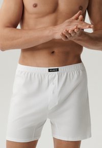 Białe bawełniane bokserki z guzikiem, elastycznym pasem i etykietą "ATLANTIC" z przodu. Gładka tekstura, luźny krój.