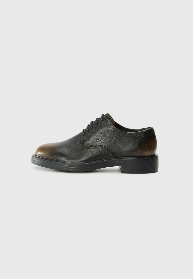 Scarpa di pelle nera con punta rotonda, design con lacci e finitura strutturata. Presenta un distintivo accento marrone scuro sul tallone.