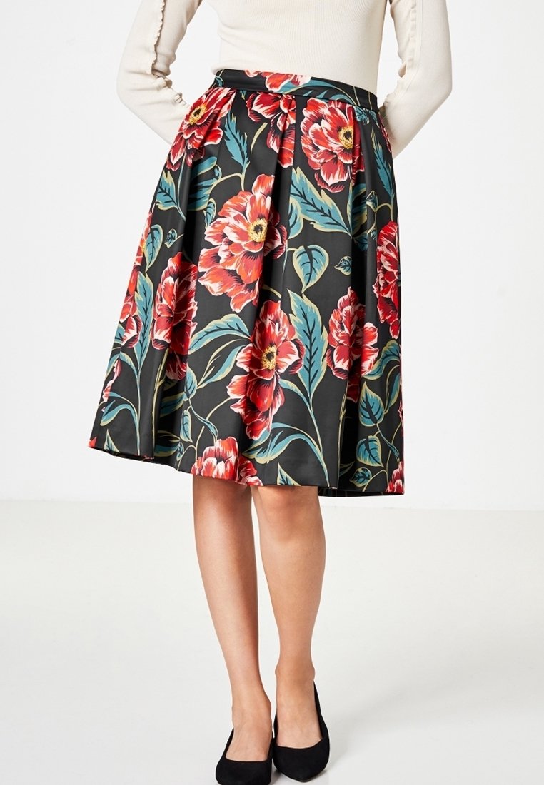 Jupe A-line florale avec de grandes fleurs rouges et roses sur un fond noir, dotée d'une taille ajustée et d'un design plissé.