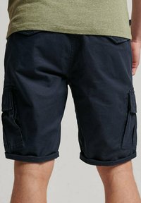 Pantaloni cargo navy con orli arrotolati, dotati di quattro tasche, un tessuto resistente e una vestibilità comoda. Nessun logo o motivo visibile.