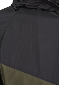 Giacca color block con parte superiore nera e parte inferiore verde oliva. Realizzata in tessuto liscio e resistente all'acqua; design leggero.