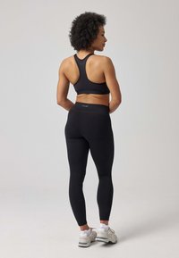 Zwarte sportbeha en hoge taille legging van rekbare stof. De beha heeft een racerback ontwerp, terwijl de leggings een gladde textuur hebben.
