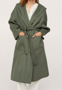 Long, olive-green wrap coat made from a soft fabric. Features a wide collar, front pockets, and a matching tie belt at the waist.