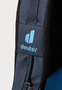 Blue fabric patch featuring "deuter" logo in light blue stitching, with dark textured material on the surrounding edge and solid blue background.