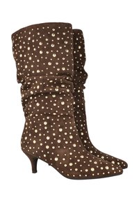 Botas de ante marrón con un diseño caído, que presentan tachuelas metálicas doradas de diferentes tamaños, puntera afilada y un tacón bajo tipo kitten.