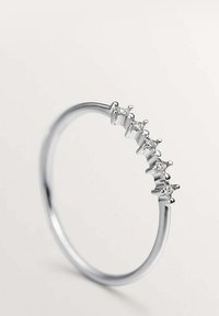 Anillo de plata con cinco gemas transparentes engastadas en garra. La banda lisa presenta un diseño minimalista, destacando un estilo moderno y elegante.