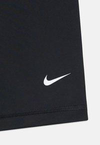 T-shirt de sport noir en tissu lisse et léger. Présente un logo Nike blanc, des coutures plates et un design ajusté.