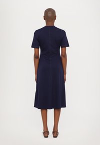 Marineblaue knielange Kleid mit kurzen Ärmeln, geradem Schnitt, Rückennahtdetail und glatter Oberfläche.