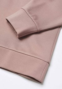 Tela de sudadera rosa claro con una textura suave. Presenta una manga y dobladillo doblados, mostrando un diseño limpio y moderno.