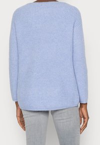 Light blue knitted sweater with a loose fit, ribbed texture, round neckline, and long sleeves. Worn over light gray pants.